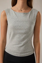 Woman wearing a sleeveless top with a subtle pattern against a neutral background