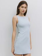 Woman wearing a light blue sleeveless dress against a white background