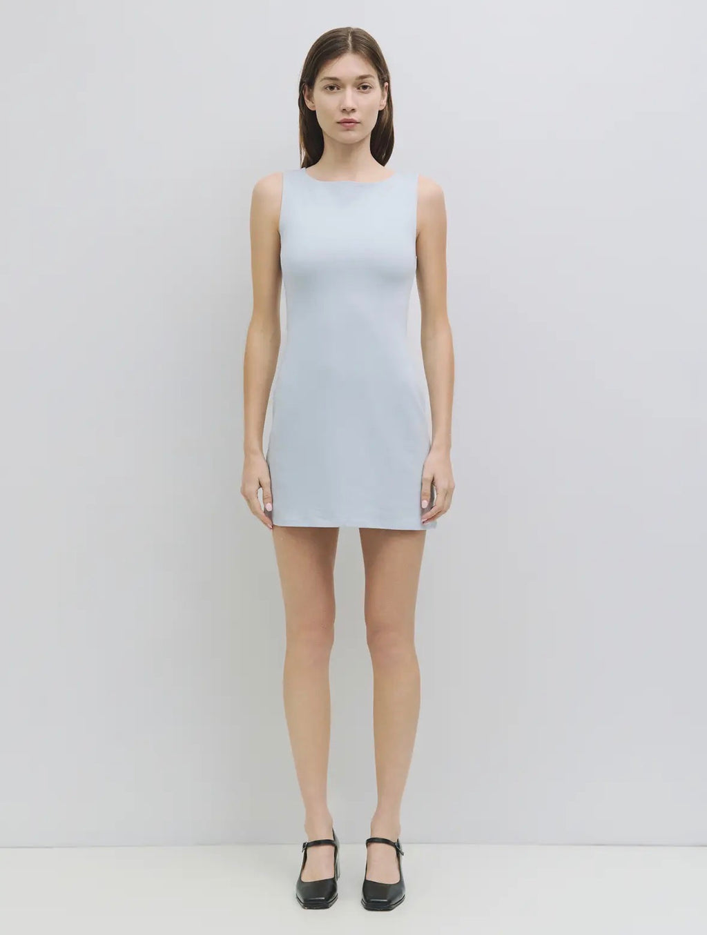 Woman wearing a light gray sleeveless dress on a white background