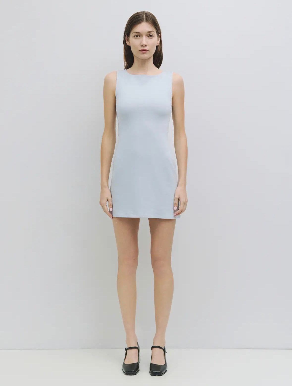 Woman wearing a light gray sleeveless dress on a white background