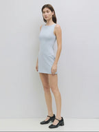 Woman wearing a light blue sleeveless dress against a white background