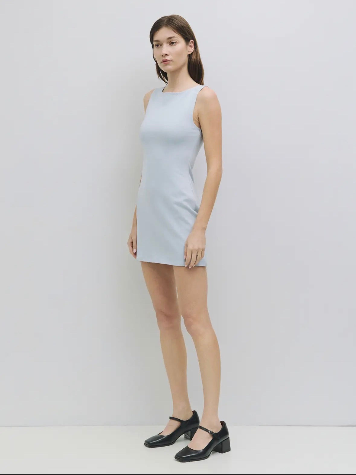 Woman wearing a light blue sleeveless dress against a white background
