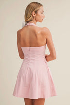 Woman wearing a pink halter neck dress against a beige background
