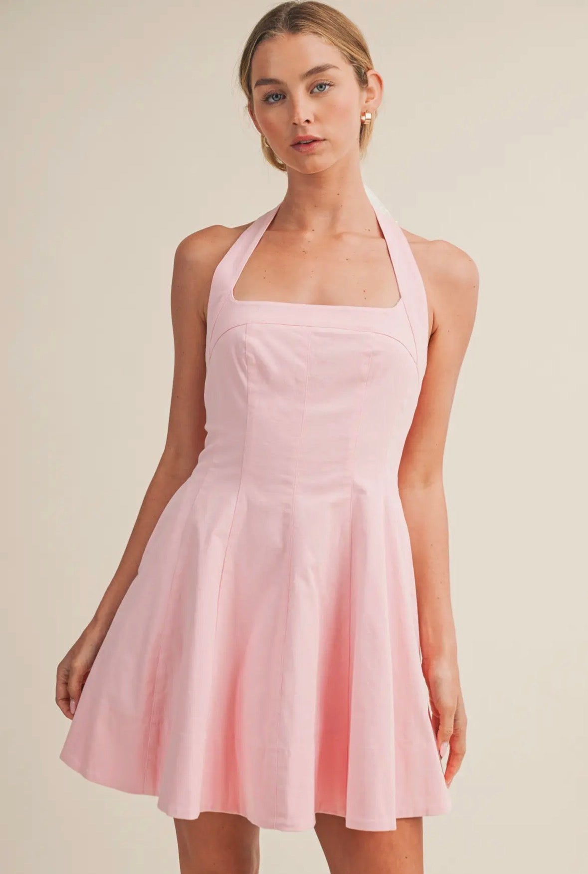Woman wearing a pink halter dress against a neutral background