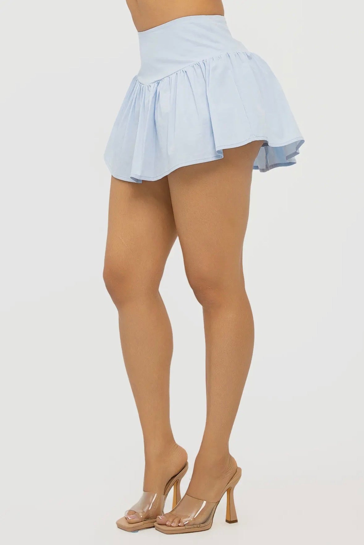 Person wearing a light blue skirt and beige tights on a white background