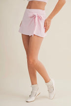 Person wearing a light pink skirt with a white background