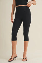Person wearing black capri leggings on a beige background