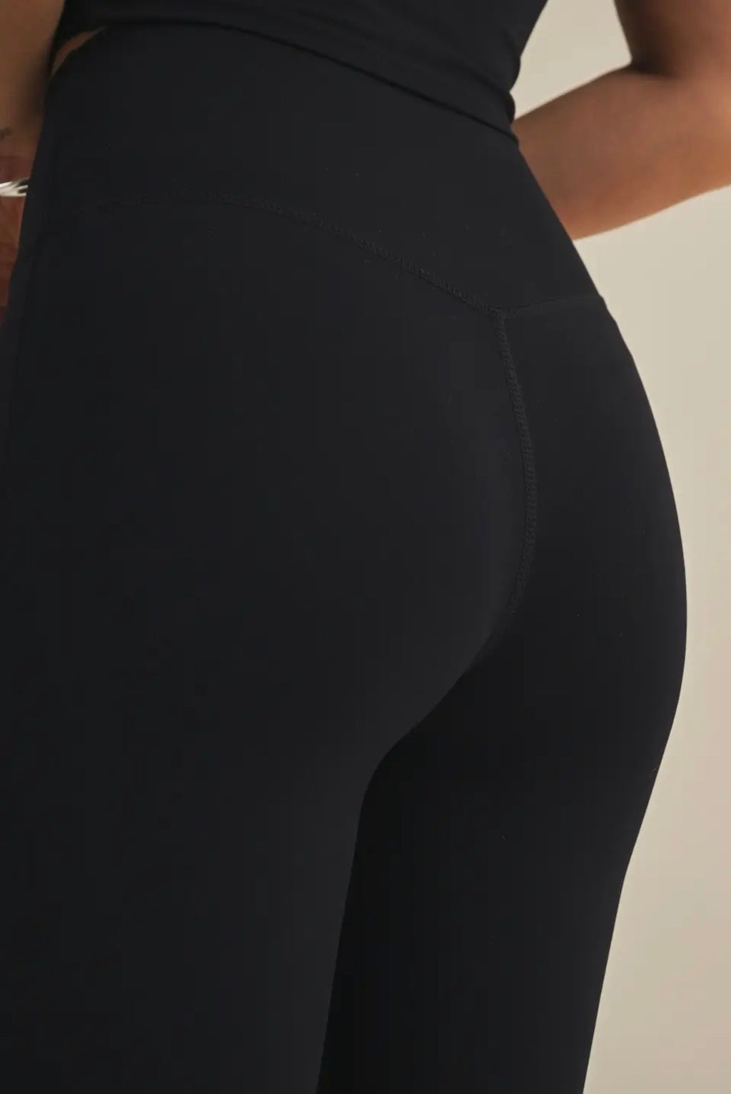 Black leggings worn by a person on a beige background