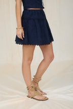 Person wearing a navy blue skirt with lace trim on a neutral background