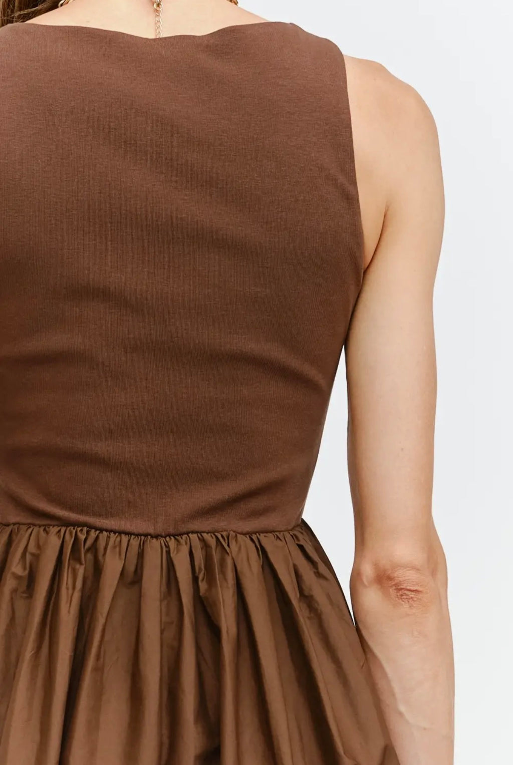 Brown sleeveless top worn by a person on a white background